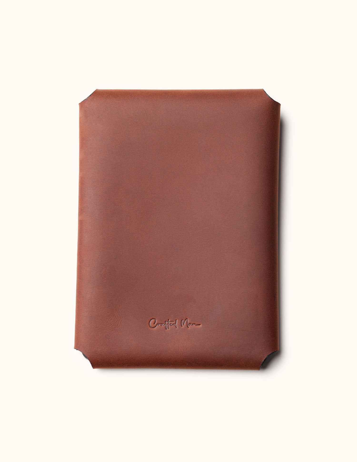 Back view of a brown full-grain leather Kindle sleeve embossed with the CraftedMan logo, showcasing the clean stitching-free design