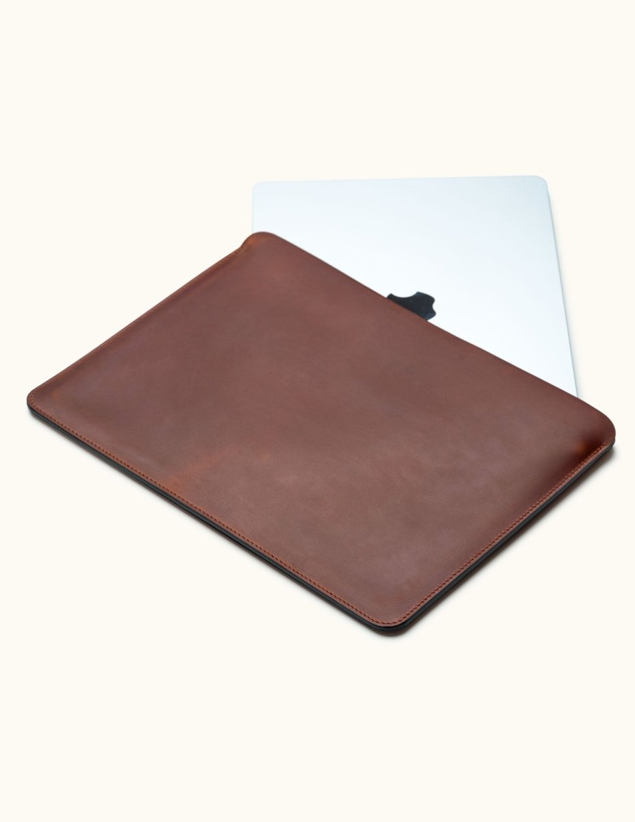 Slim full-grain leather MacBook Air sleeve in brown, customizable, shown partially open with laptop inside