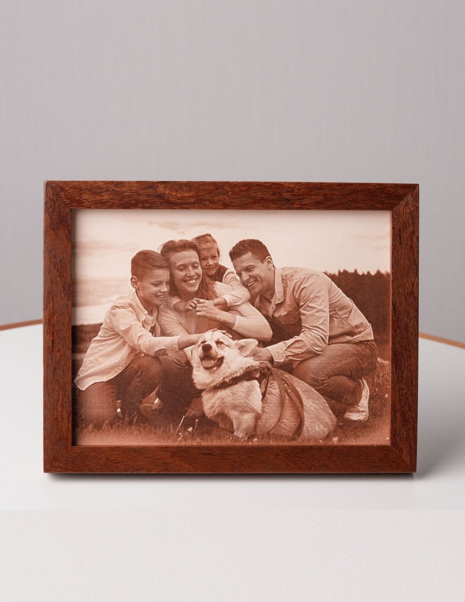 Personalized laser-engraved leather photo of a smiling family with their dog, framed in wood and displayed on a table — a heartfelt custom gift for pet lovers and family keepsakes