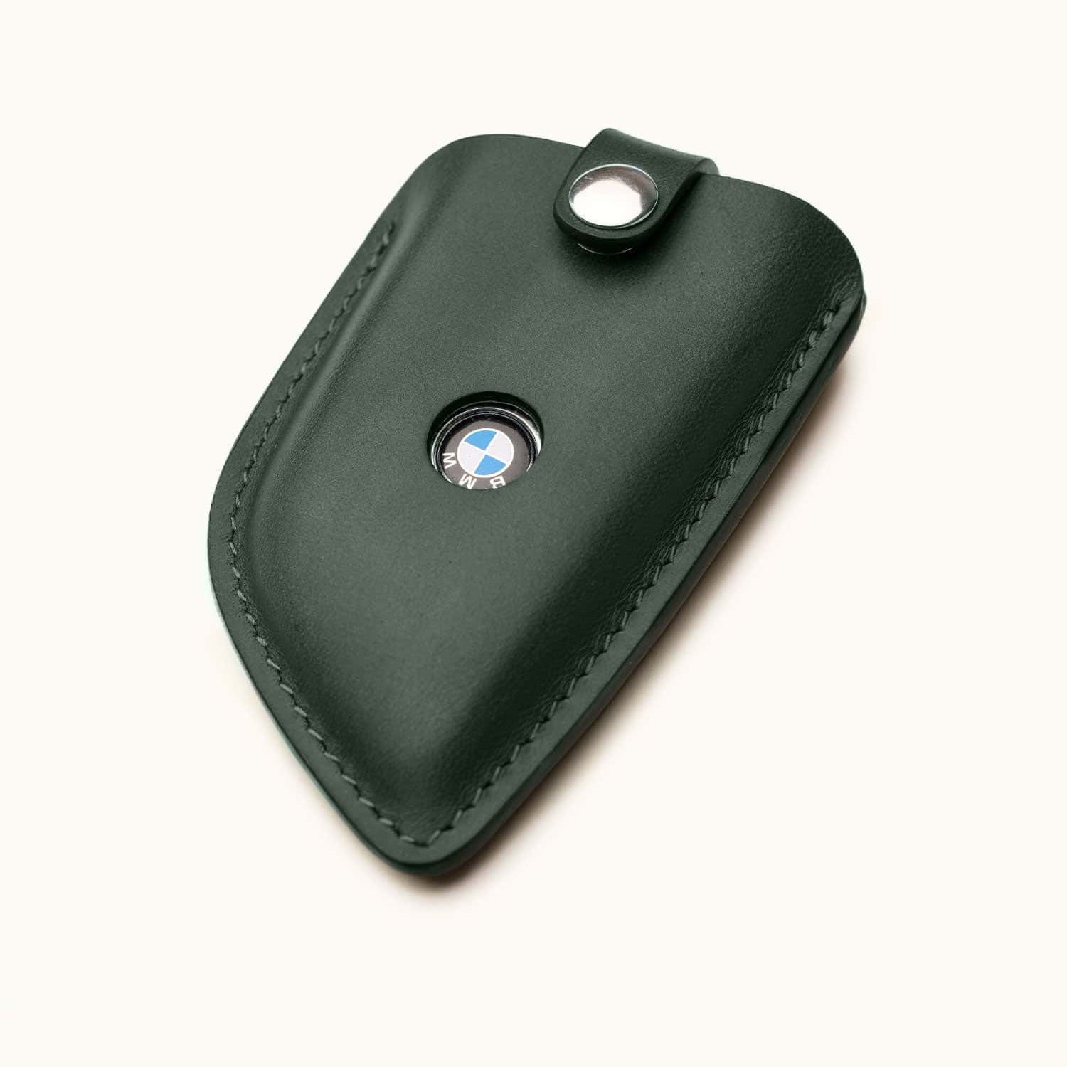 Angled view of green leather key fob cover for BMW G Series smart key with snap button and visible logo window