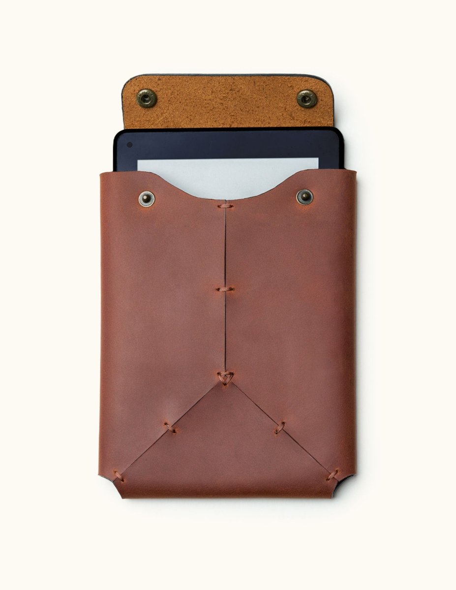 Front view of a handcrafted leather Kindle sleeve with snap button closure, shown with a Kindle device partially inserted inside