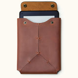 Front view of a handcrafted leather Kindle sleeve with snap button closure, shown with a Kindle device partially inserted inside