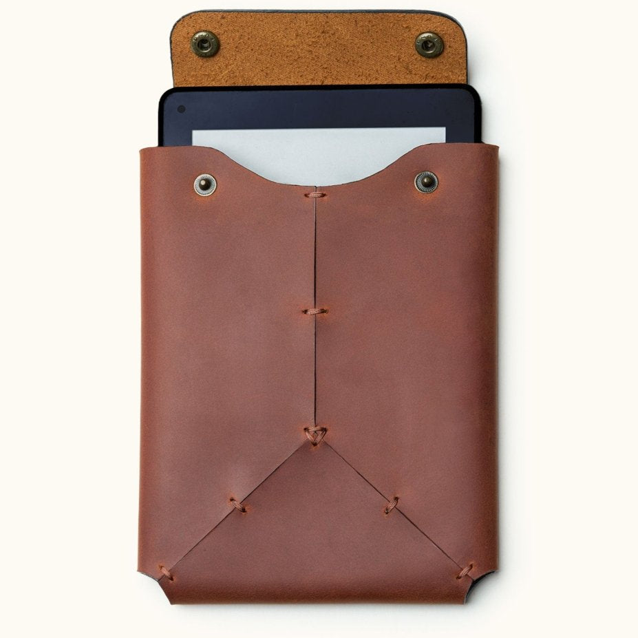 Front view of a handcrafted leather Kindle sleeve with snap button closure, shown with a Kindle device partially inserted inside