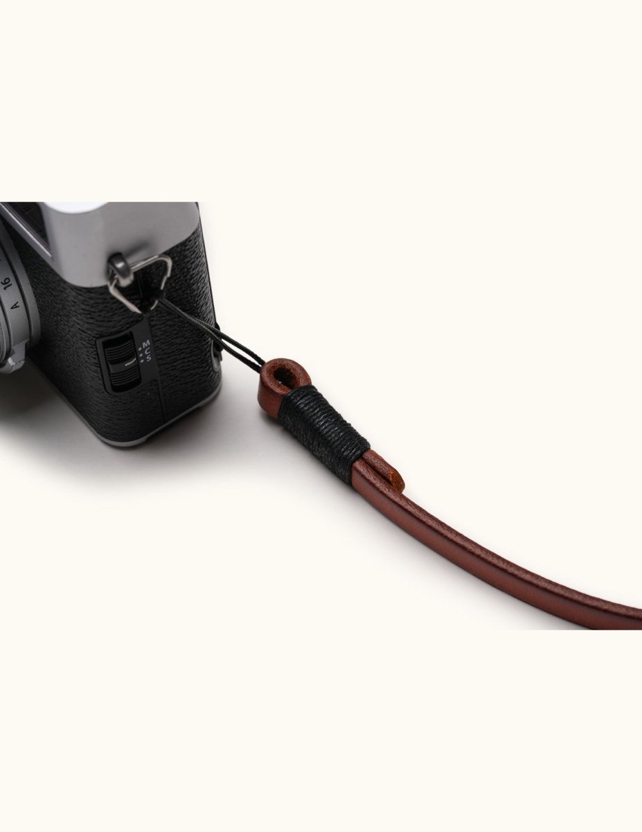 Close-up of leather camera strap securely attached to Fujifilm camera with waxed thread and loop detail
