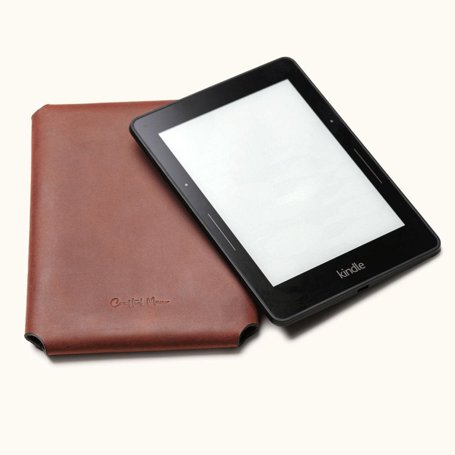 Handcrafted leather Kindle case in brown, designed for Kindle Paperwhite, Oasis, and Scribe models. Shown with a Kindle device partially inserted