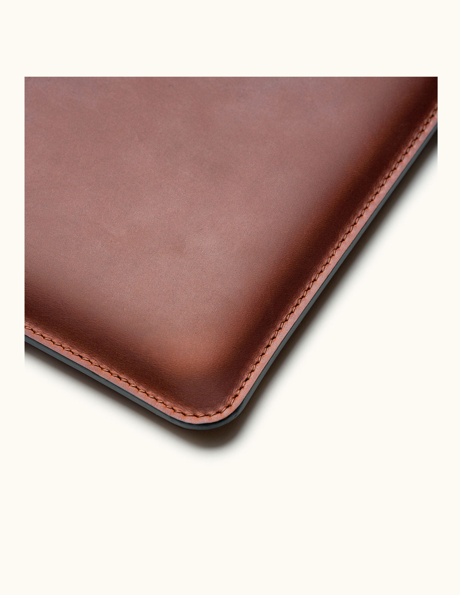 Close-up of a vintage brown leather sleeve corner, showing the leather texture, rounded edge and neat stitching.