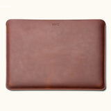 Front view of a vintage brown leather laptop sleeve with a small monogram near the top center and stitched edges.