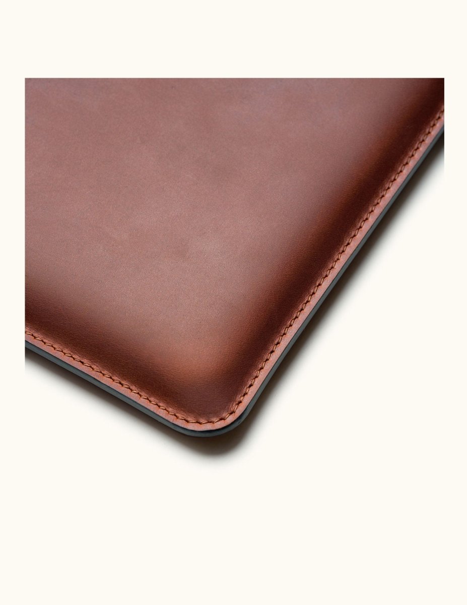 Close-up of corner stitching on vintage brown full-grain leather MacBook Pro sleeve, showing craftsmanship and texture