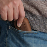 Close up of a man taking a custom brown crazy horse leather AirPods Pro 3 case out of his blue jeans front pocket. Everyday carry tech accessory.