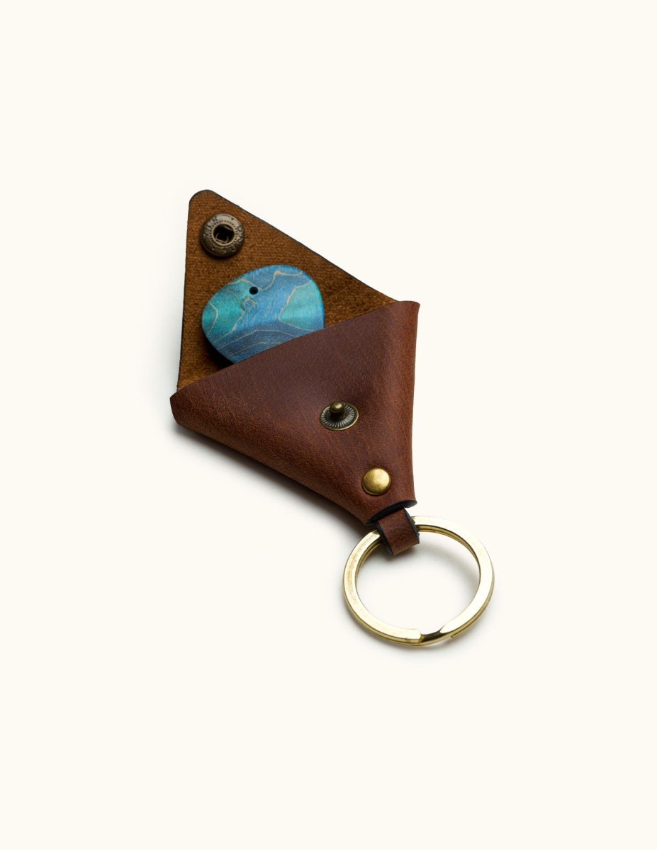 Open triangular leather guitar pick keychain holder with brass snap and visible blue pick inside