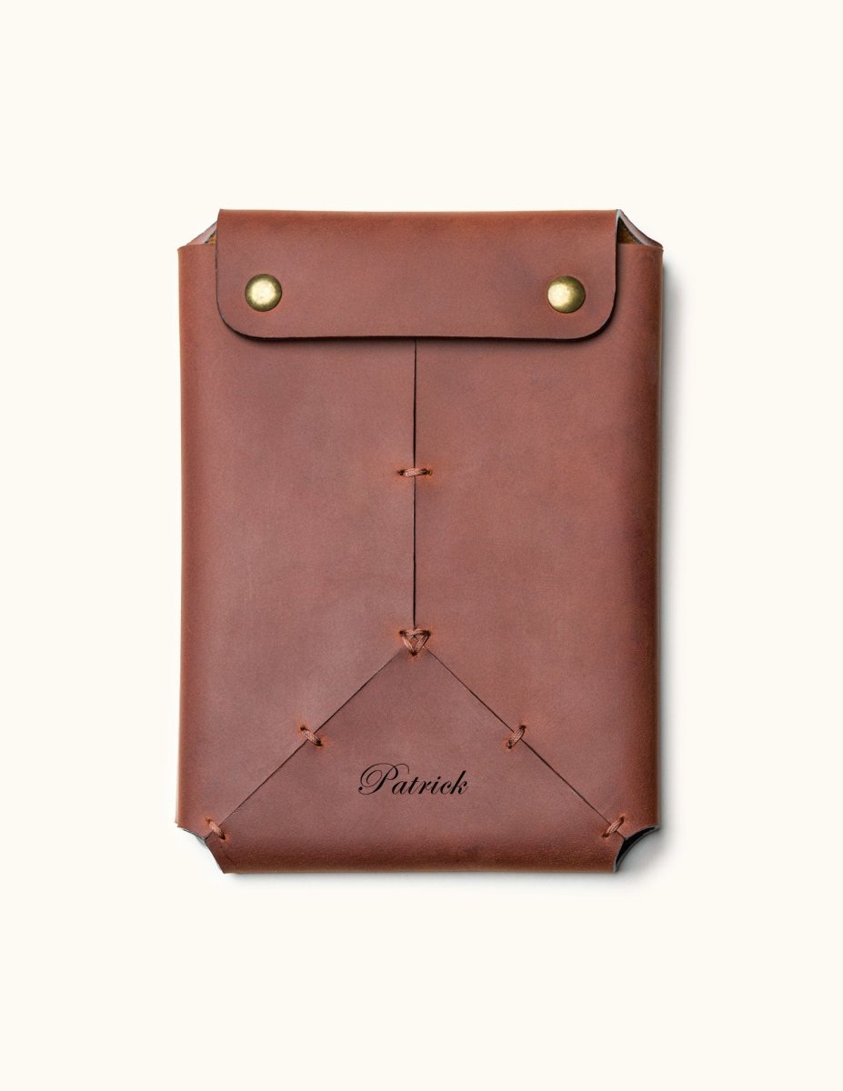 Personalized brown leather Kindle sleeve with snap button closure, engraved with the name "Patrick" and featuring handcrafted stitching details