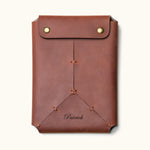 Personalized brown leather Kindle sleeve with snap button closure, engraved with the name "Patrick" and featuring handcrafted stitching details
