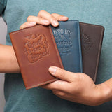 Person holding three personalized leather passport covers in Vintage Brown, Navy, and Coffee – travel-ready and customizable gifts