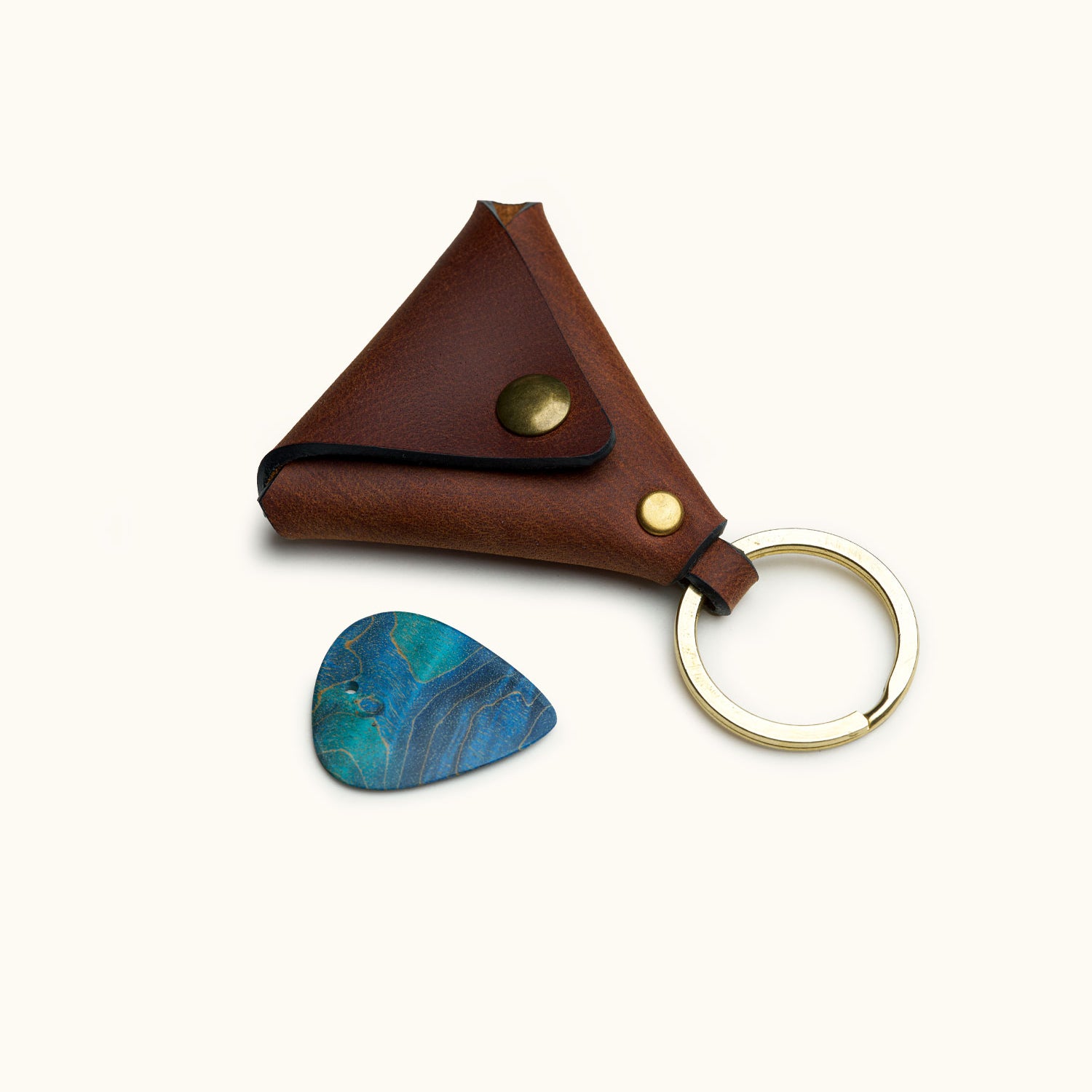 Triangular leather guitar pick holder with keyring and brass snap, shown with a blue pick
